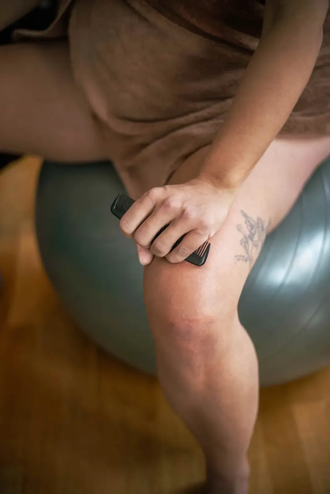 Födande kvinna sitter på en pilatesboll och håller två förlossningskammar hårt i handen som smärtlindring under en värk.