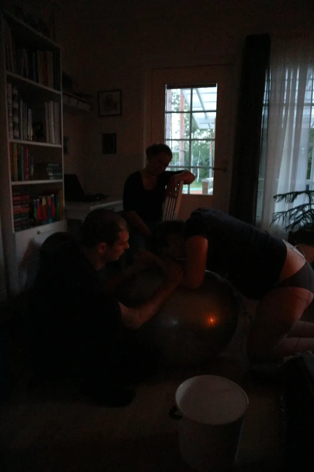 Jenny lutar sig över en pilatesboll i vardagsrummet medan hennes man sitter intill och stöttar.
