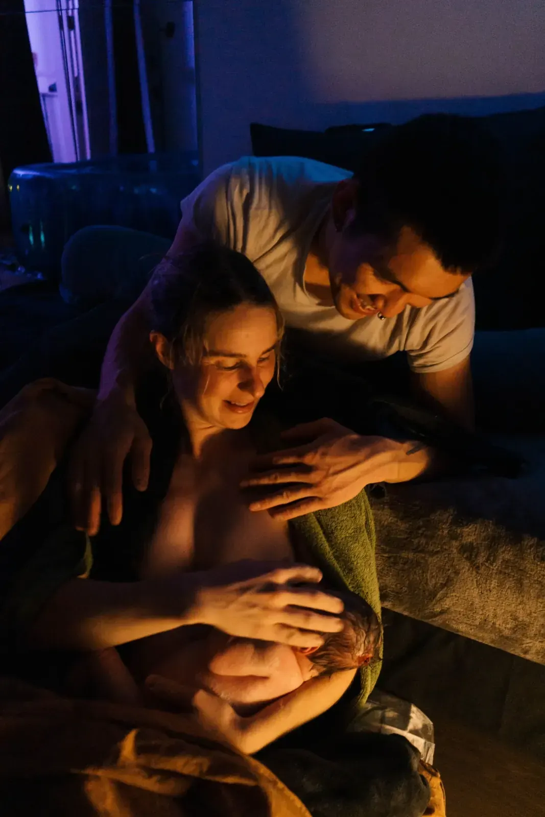 Jessica och Teddy håller om nyfödde Rio i levande ljus efter födseln, med poolen i bakgrunden.