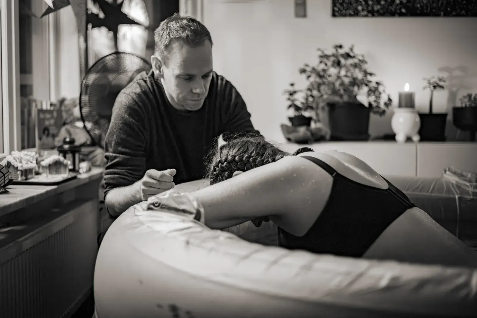 Dan sitter vid poolkanten och håller Maddos hand medan hon vilar pannan mot poolens kant under en värk.