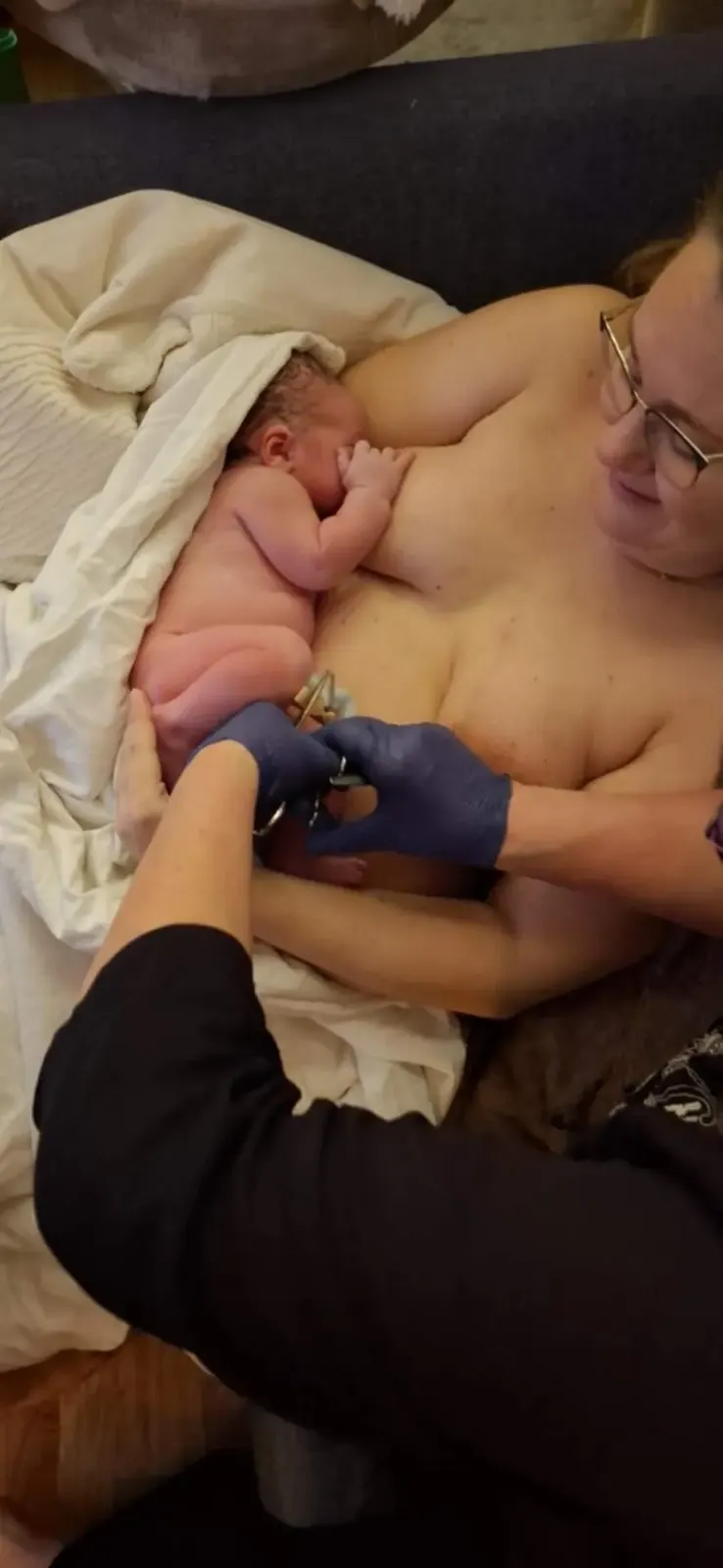 Den nyfödde pojken vilar mot Lisettes bröst medan navelsträngen klipps.