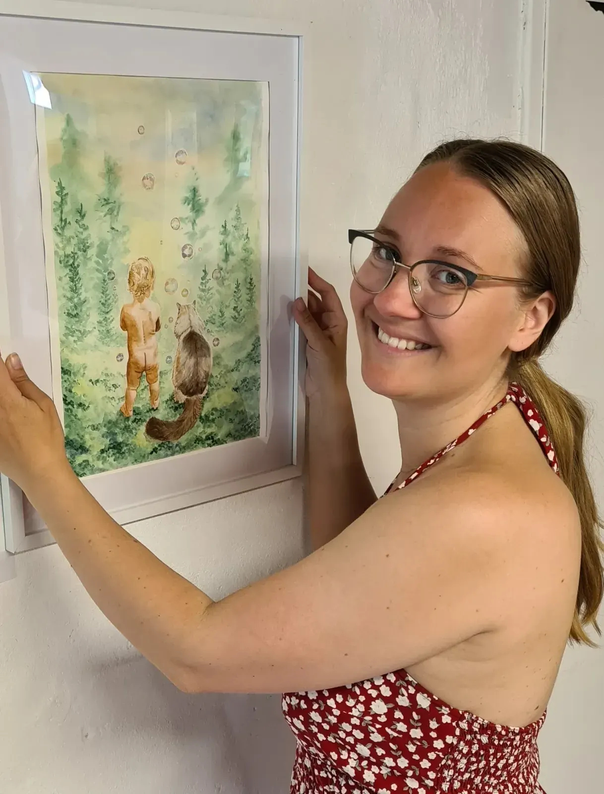 Porträtt av Lisette Wennström som hänger upp en av sina akvareller.